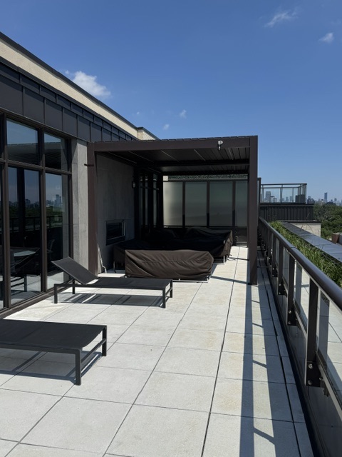 Rooftop terrace walkway with loungers, pergola and skyline views
