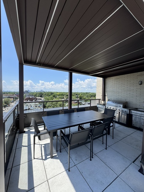 Covered rooftop dining table with BBQs and treetop views
